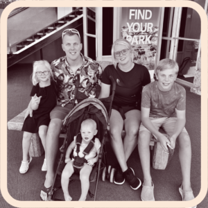 Black and white photo of family of five sitting on bench smiling